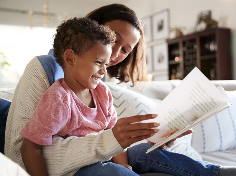 Black mother reading a book to her Black daughter